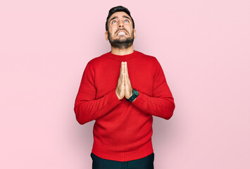 Young hispanic man wearing casual clothes begging and praying with hands together with hope...