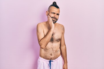 Fototapeta premium Young hispanic man shirtless wearing swimsuit touching mouth with hand with painful expression because of toothache or dental illness on teeth. dentist