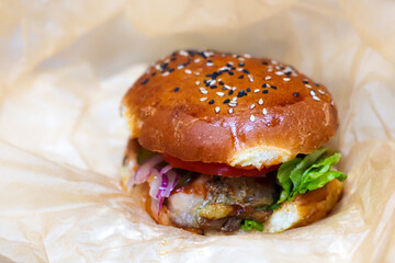 Fresh burger barbecued in craft paper. American barbecue. Big hamburger with meat steak and vegetables. Street food, fast food