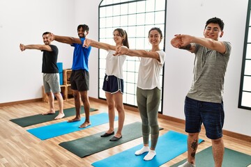 Obraz premium Group of young sporty people smiling happy training yoga at sport center.