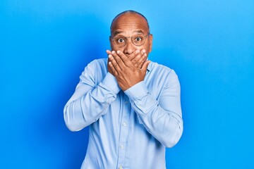 Middle age latin man wearing casual clothes and glasses shocked covering mouth with hands for mistake. secret concept.