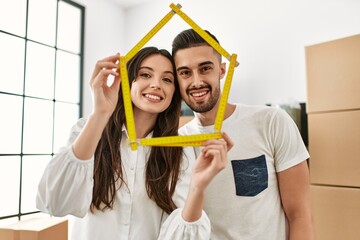 Young hispanic couple smiling happy holding house project at new home.