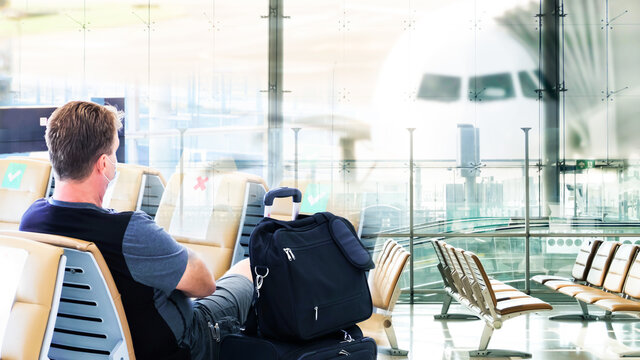 businessman with luggage in   airport Terminal. Handsome caucasian waiting for flight aircraft,terminal gate for airplane travel trip - Mobility concept and aerospace industry flight connections.