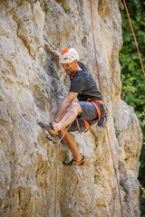 Athletic mid age man in a difficult rock climbing tour in the La Gola climbing area, Sarca Valley, Lake Garda mountains, Trentino Italy