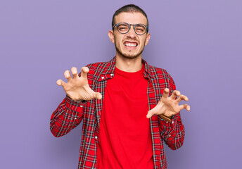 Hispanic young man wearing casual clothes smiling funny doing claw gesture as cat, aggressive and...
