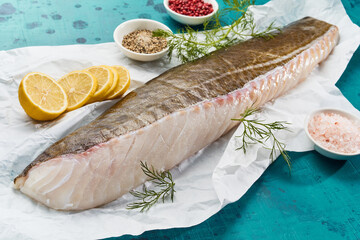 Uncooked fish fillet on paper with lemon slices