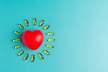 fish oil capsule and red heart on blue background