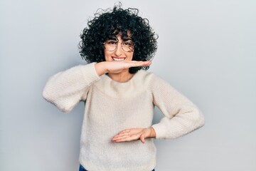 Young middle east woman wearing casual white tshirt gesturing with hands showing big and large size sign, measure symbol. smiling looking at the camera. measuring concept.