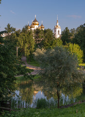 Golden domes of Uspensky Cathedral and belltower in Dmitrov near Moscow, Russia, reflecting in a pond