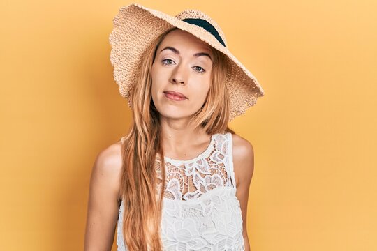 Young caucasian woman wearing summer hat relaxed with serious expression on face. simple and natural looking at the camera.