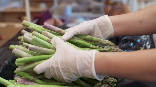  seller takes a lot of asparagus from the box and takes it away. Fresh green asparagus in the store
