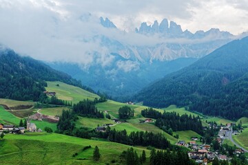 Idyllic scenery of Val di Funes in summer season with rugged peaks of Odle mountain range in background & a church in Village Santa Maddalena in the green grassy valley in Dolomiti, South Tyrol, Italy