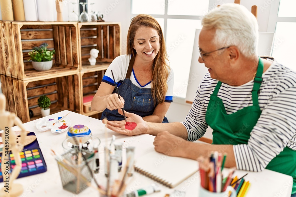 Poster Two middle age artists smiling happy painting hands at art studio.