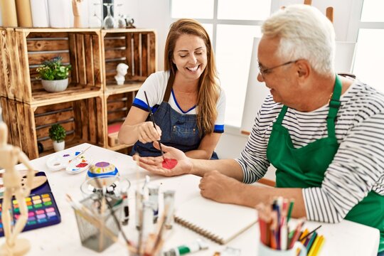 Two middle age artists smiling happy painting hands at art studio.