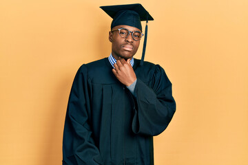 Young african american man wearing graduation cap and ceremony robe touching painful neck, sore throat for flu, clod and infection