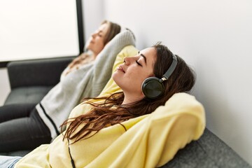 Young couple smiling happy listening to music sitting on the sofa at home. © Krakenimages.com
