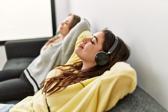 Young couple smiling happy listening to music sitting on the sofa at home.