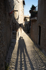 Tourist shadows in Santo Stefano di Sessanio medieval village details, historical stone buildings, ancient alley, old city stone architecture. Abruzzo, Italy.