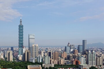 Fototapeta na wymiar Aerial panorama of Downtown Taipei, vibrant capital city of Taiwan, with prominent Taipei 101 Tower among skyscrapers in Xinyi District & Yangmingshan Mountain on distant horizon under blue sunny sky