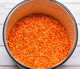 raw dry red lentils in metal bowl.  quick-cooking  red lentils legume on white wooden  background close up 