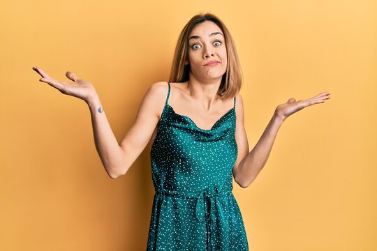 Young caucasian blonde woman wearing elegant party dress clueless and confused with open arms, no idea and doubtful face.