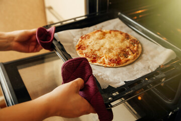 girl gets homemade pizza from the oven 