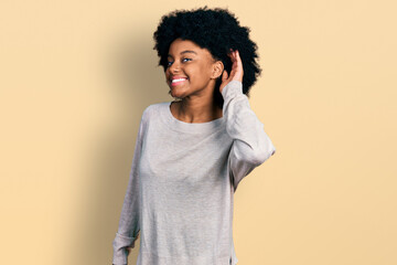 Young african american woman wearing casual clothes smiling with hand over ear listening an hearing to rumor or gossip. deafness concept.