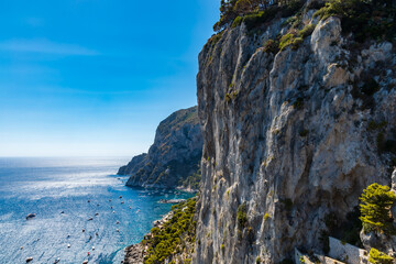 Edge of high cliff full of high green trees at sunny day on Capri island