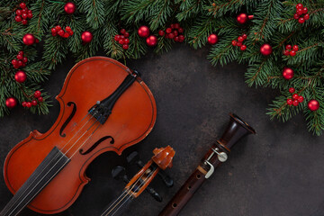 Fototapeta na wymiar Old violin and flute with fir-tree branches with Christmas decor. Christmas and New Year's concept. Top view, close-up on dark concrete background