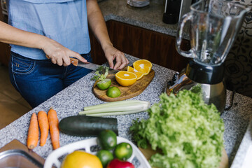 Latin Woman making green smoothie or Detox juice in kitchen at Home in healthy eating concept in Mexico
