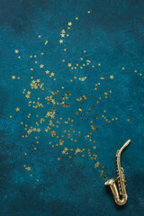 Miniature golden saxophone copy on the blue background with  glitter.