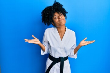 African american woman with afro hair wearing karate kimono and black belt clueless and confused...