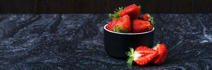Strawberries on black marble. Ripe strawberries in a saucer on a black background. Place to insert...