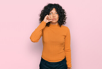 Young hispanic woman wearing casual clothes mouth and lips shut as zip with fingers. secret and...