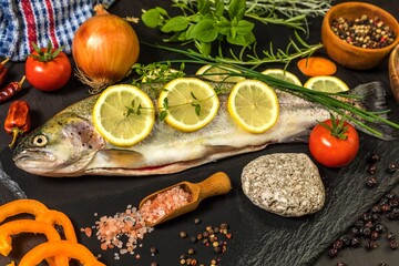 Raw trout on a black wooden table. Home preparation of trout.Healthy diet food. Fresh fish ready for grilling. Fishing industry.