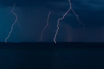Naklejka na ściany i meble Thunderstorm with lightning bolts strikes in night stormy sky