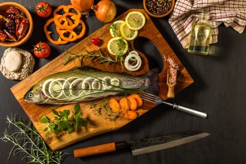 Raw trout on a black wooden table. Home preparation of trout.Healthy diet food. Fresh fish ready for grilling. Fishing industry.
