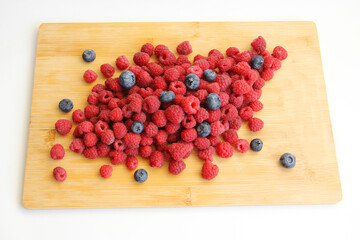 wild summer berries blueberries and raspberries on a wooden background
