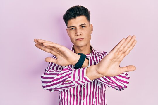 Young hispanic man wearing casual clothes rejection expression crossing arms doing negative sign, angry face