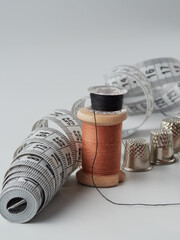 A pile of wooden buttons, a needle, old thimbles, scissors and a spool of cotton thread on a white...