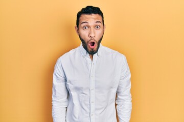 Hispanic man with beard wearing business shirt afraid and shocked with surprise expression, fear and excited face.