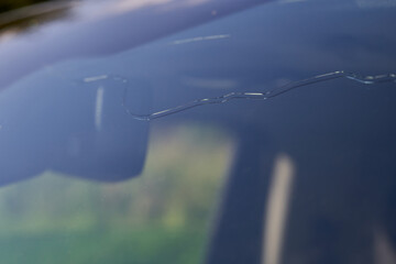 Long crack in the windshield of a car. Caused by hail and stone impact. Insurance claim.