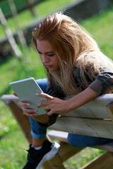 Young blond woman draped over a rustic park bench