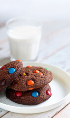 Chocolate soft cookies decorate topping with multi-colored candy. with a glass of milk .