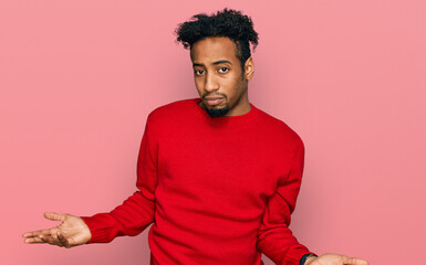 Young african american man with beard wearing casual winter sweater clueless and confused with open...