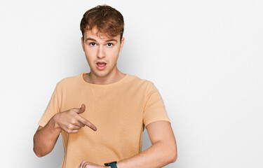 Young caucasian man wearing casual clothes in hurry pointing to watch time, impatience, upset and...