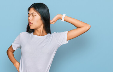 Beautiful young asian woman wearing casual white t shirt stretching back, tired and relaxed, sleepy and yawning for early morning