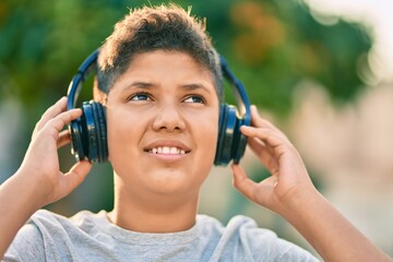 Adorable latin boy smiling happy using headphones at the city.