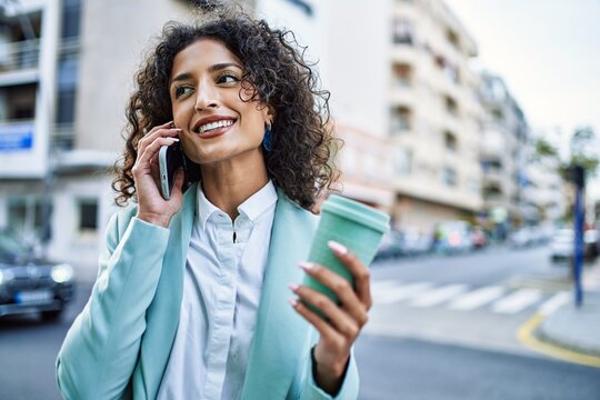 Young hispanic business woman wearing professional look smiling confident at the city speaking on the phone