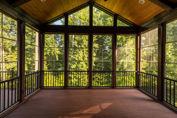 Modern new screened porch with plastic windows and composite floor with summer woods in the background.